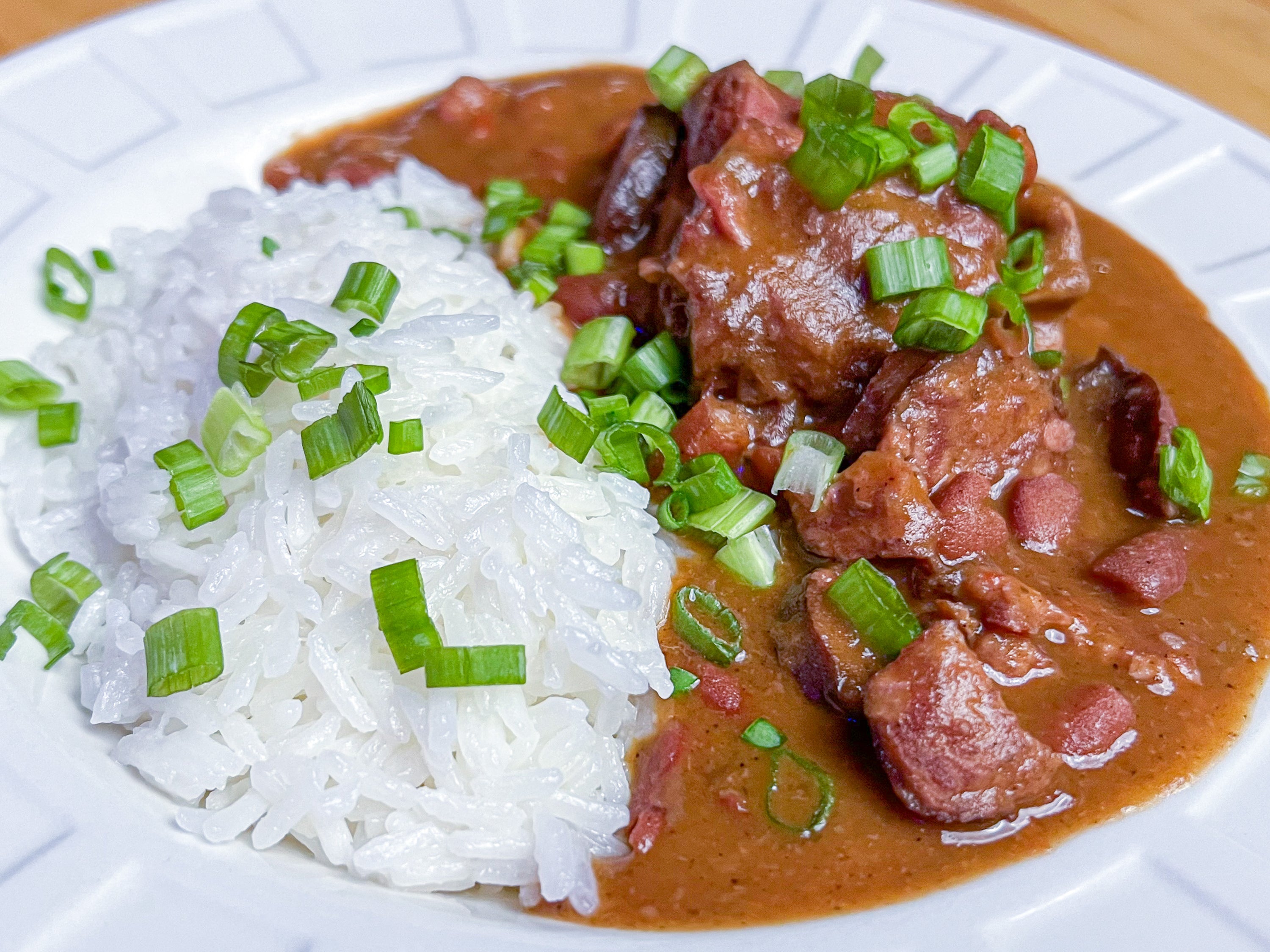 Southern style red beans and rice with sausage and turkey in a white bowl garnished with green onions